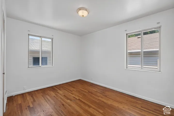 Room featuring wood-finish flooring, two large windows, white walls, and a ceiling-mounted light fixture