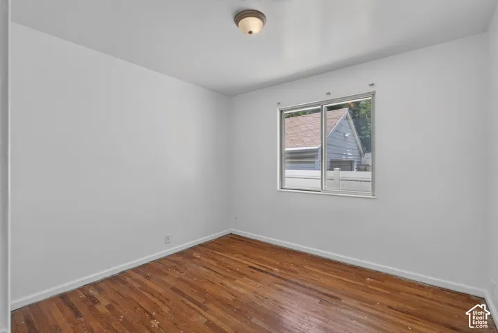 Room featuring wood-finish flooring, white painted walls, a single window, and a flush-mount ceiling light