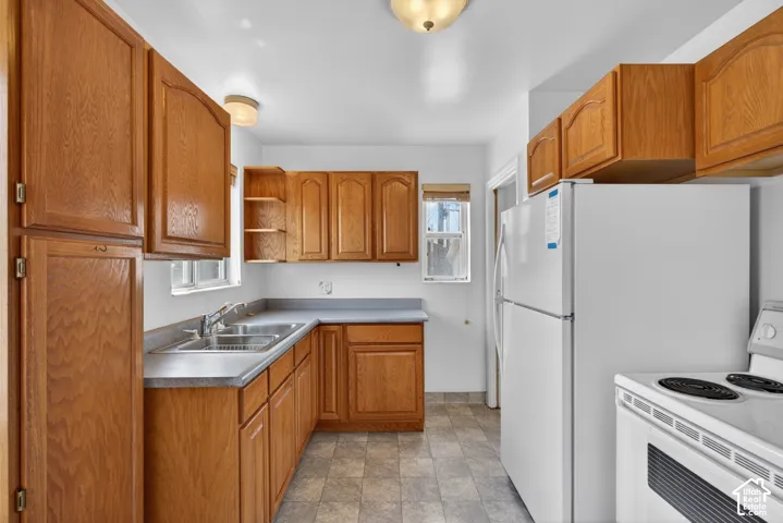 Kitchen featuring white appliances, open shelves, wood finish cabinetry, and stone finish floors