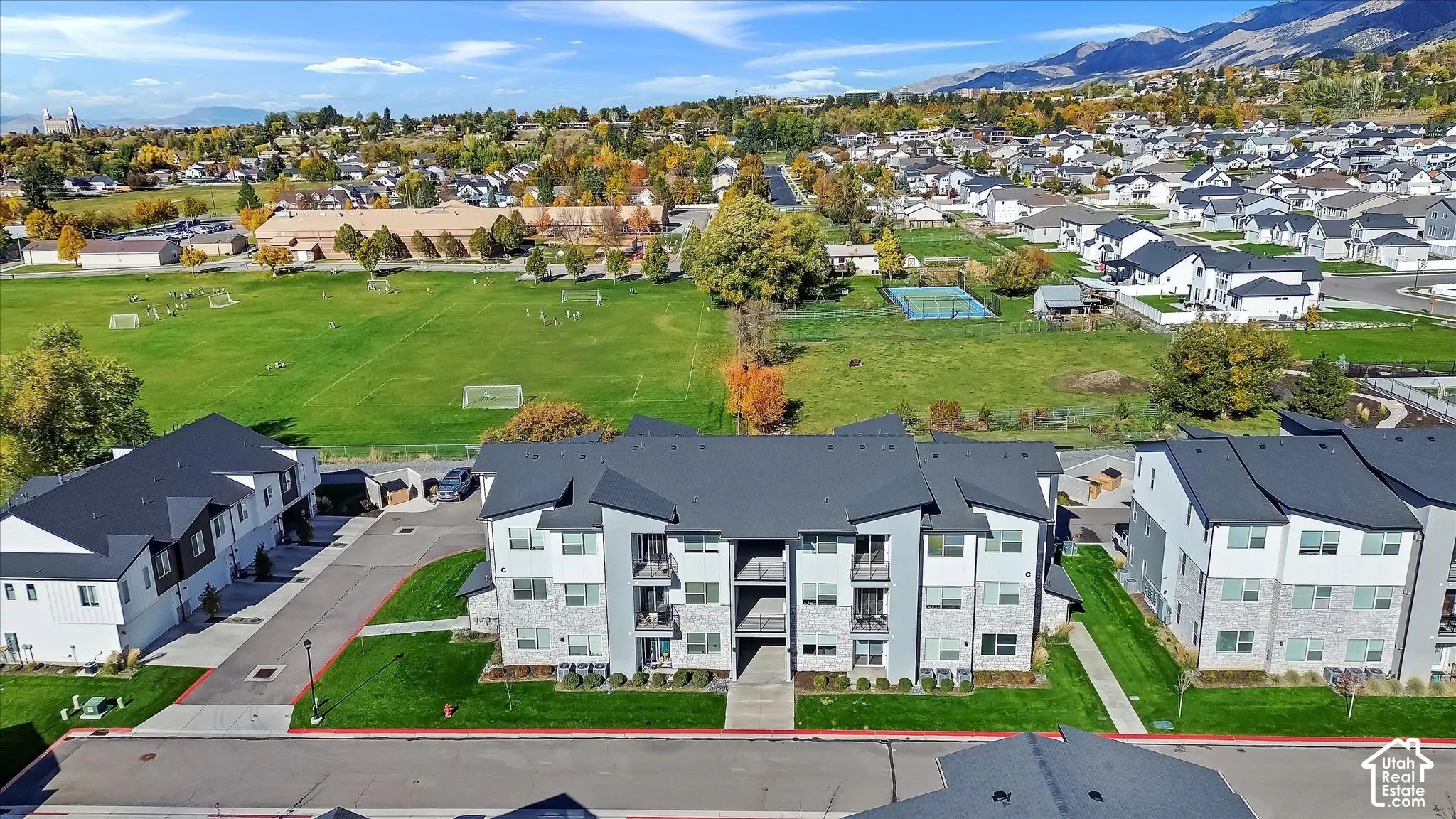 Multi-story residential complex featuring stone and siding exterior, steep-pitched rooflines, private balconies, and proximity to open green space and mountain terrain