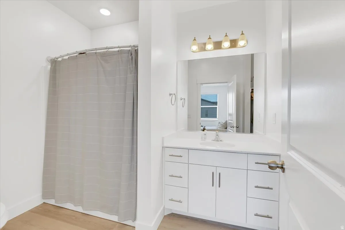 Full bathroom with vanity, a stall shower, and light wood finished floors