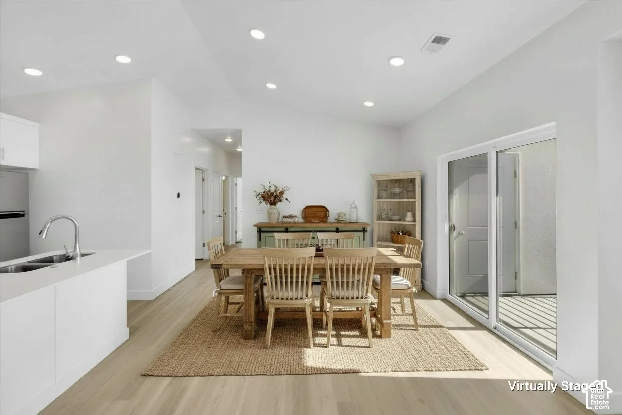 Vaulted ceilings with recessed lighting, wood-finish flooring, and sliding glass doors