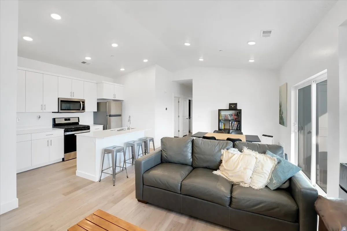 Living area with light wood-type flooring, lofted ceiling, and recessed lighting