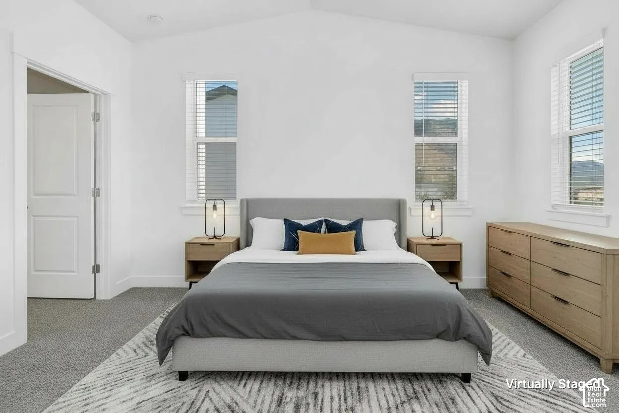Primary Suite, vaulted ceilings, carpeted flooring, and multiple windows with horizontal blinds