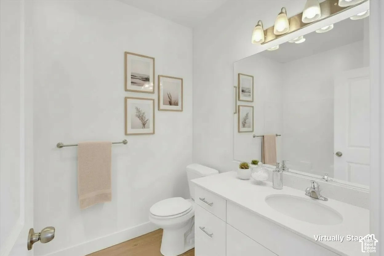 Bathroom featuring a white vanity cabinet with a stone countertop, an integrated oval basin, a full-width wall-mounted mirror, and a multi-bulb light fixture