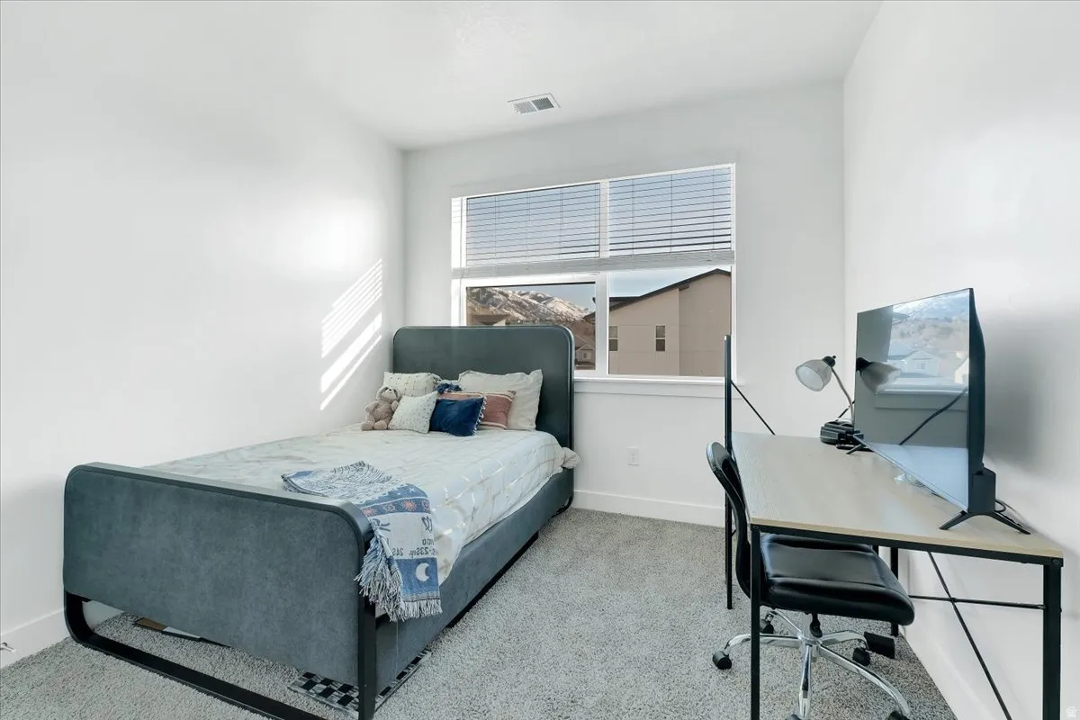 Carpeted bedroom with a desk and baseboards