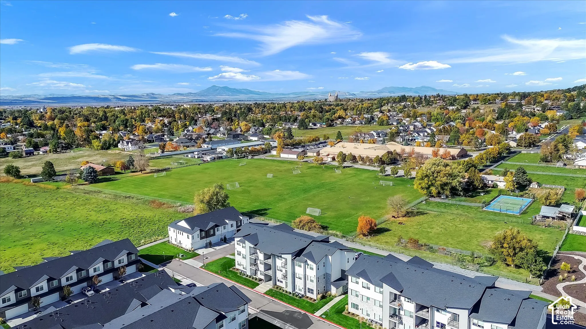 Aerial perspective of multi-family residences featuring dark-toned pitched roofing, neutral siding, and a mountain backdrop
