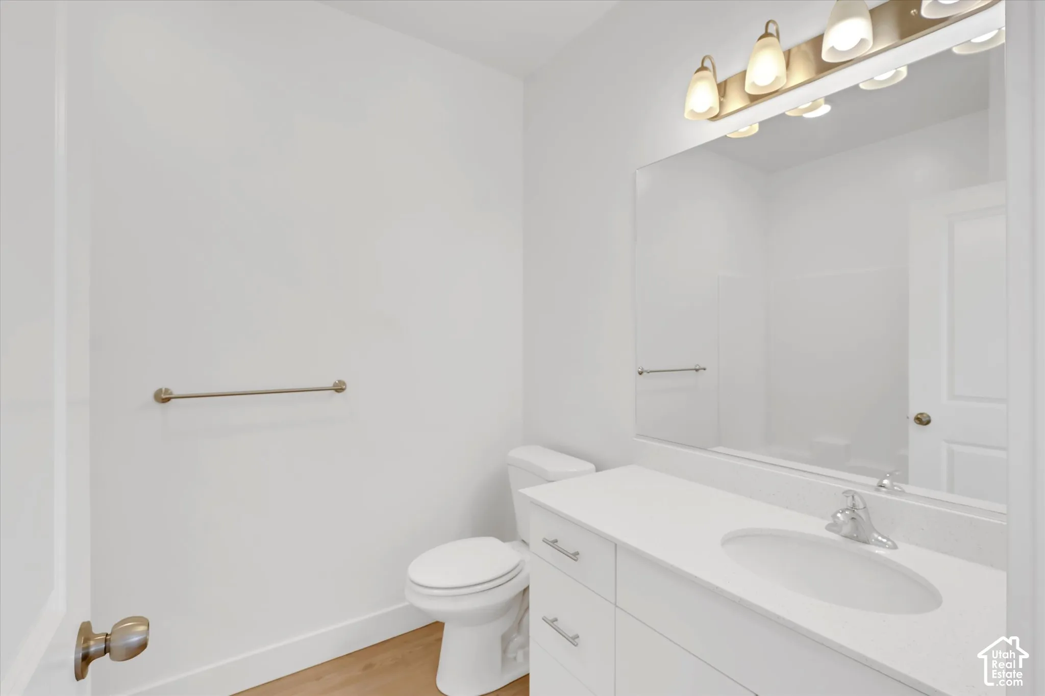 Bathroom featuring a white vanity with a composite countertop, an undermount sink, a large wall-mounted mirror, and a multi-light fixture