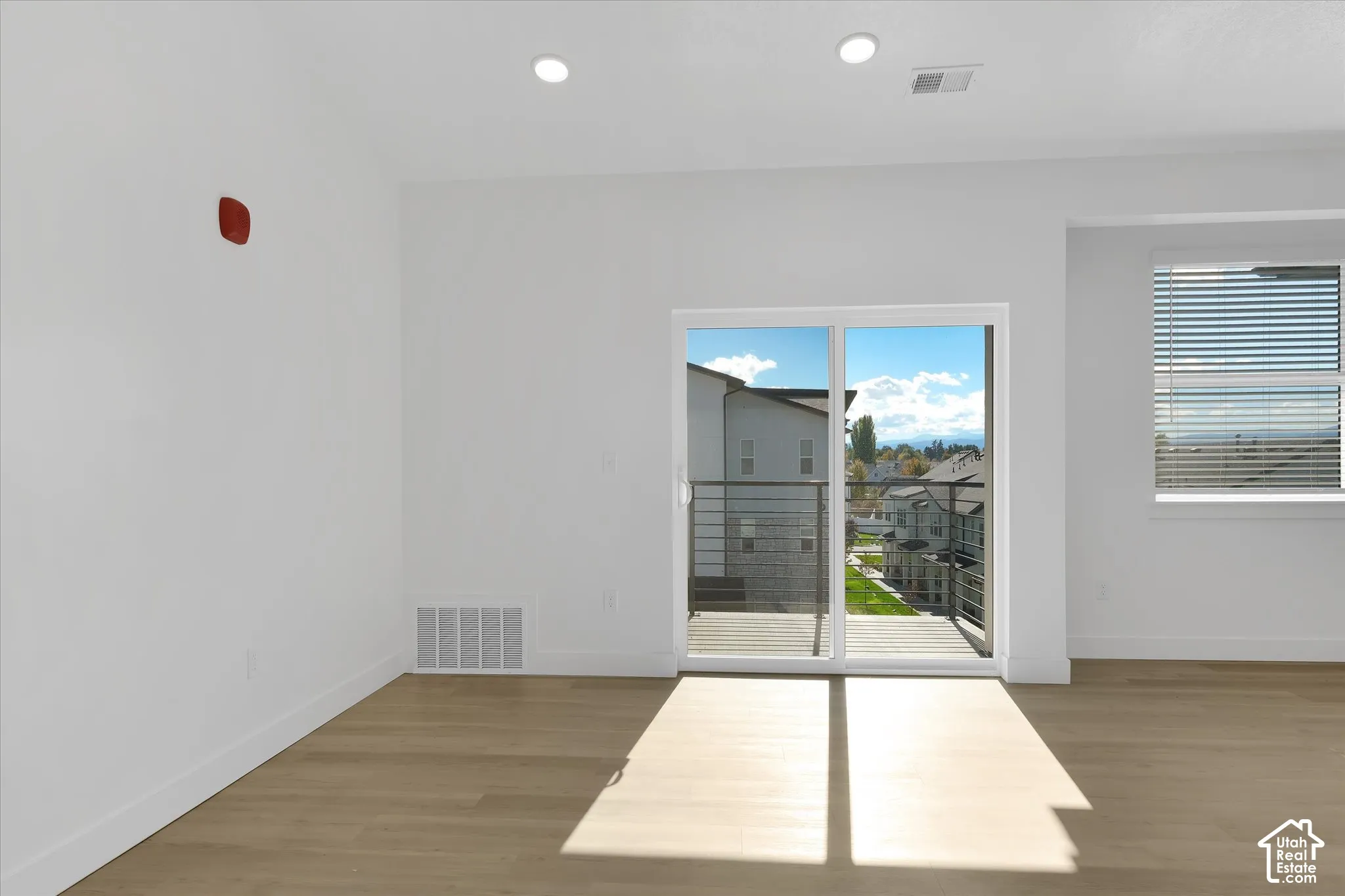 Interior space featuring recessed lighting, wood-finish flooring, sliding glass door with balcony access, and a metal-railing exterior terrace