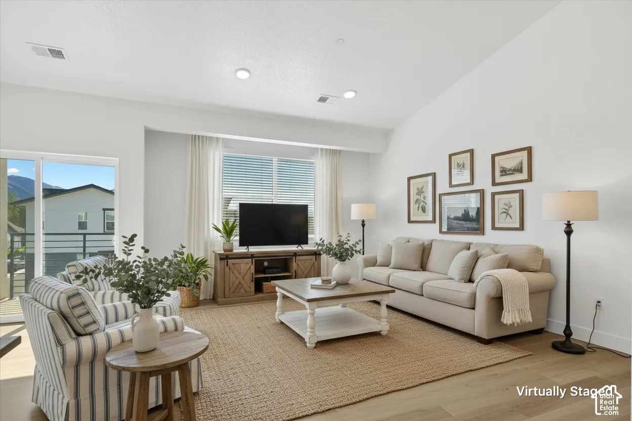 Vaulted ceilings, wood-finish flooring, recessed lighting, and large sliding glass door