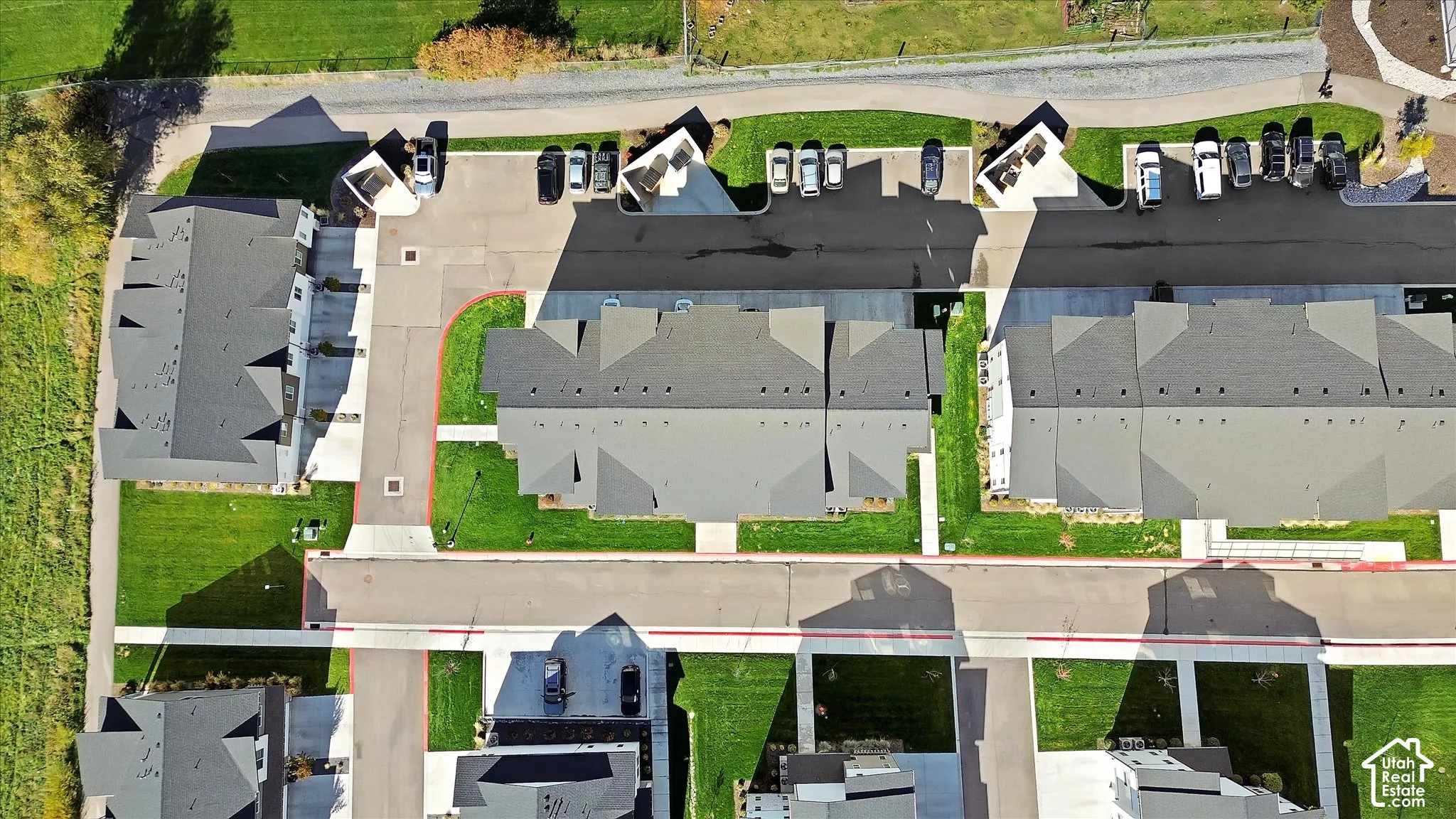 Aerial perspective of residential complex featuring paved private roadways, designated asphalt parking areas, concrete walkways, and landscaped grass lawns