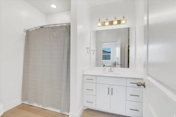 Full bathroom with vanity, a stall shower, and light wood finished floors