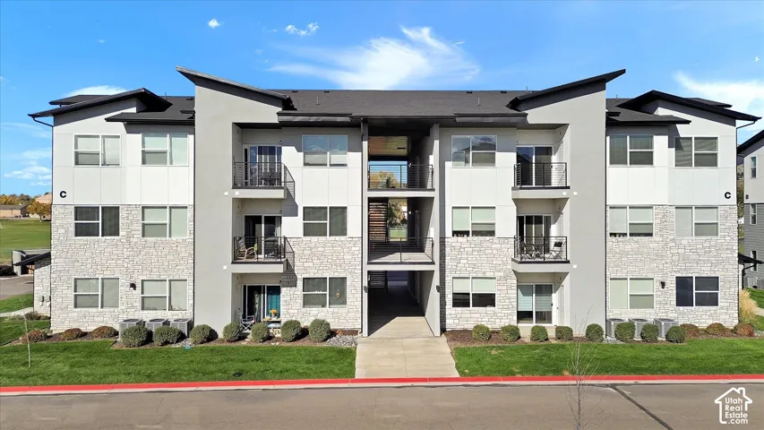 Contemporary multi-story exterior featuring a mix of stucco and stone-finish siding, shed-style rooflines, and private metal-railing balconies