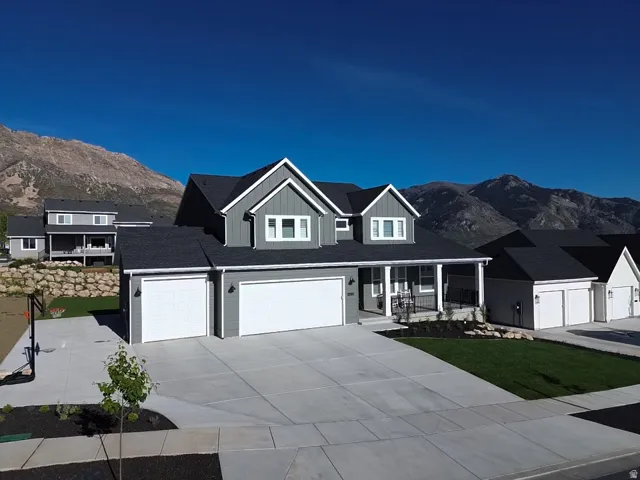 Contemporary home with a mountain backdrop, featuring a two-car garage, established front landscaping, and a covered porch entry