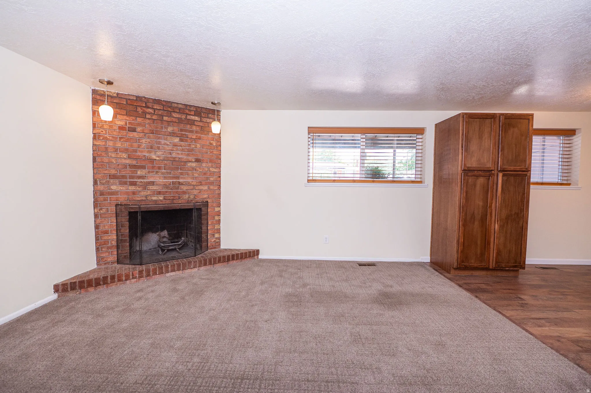 Corner brick fireplace with hearth, complemented by pendant lighting