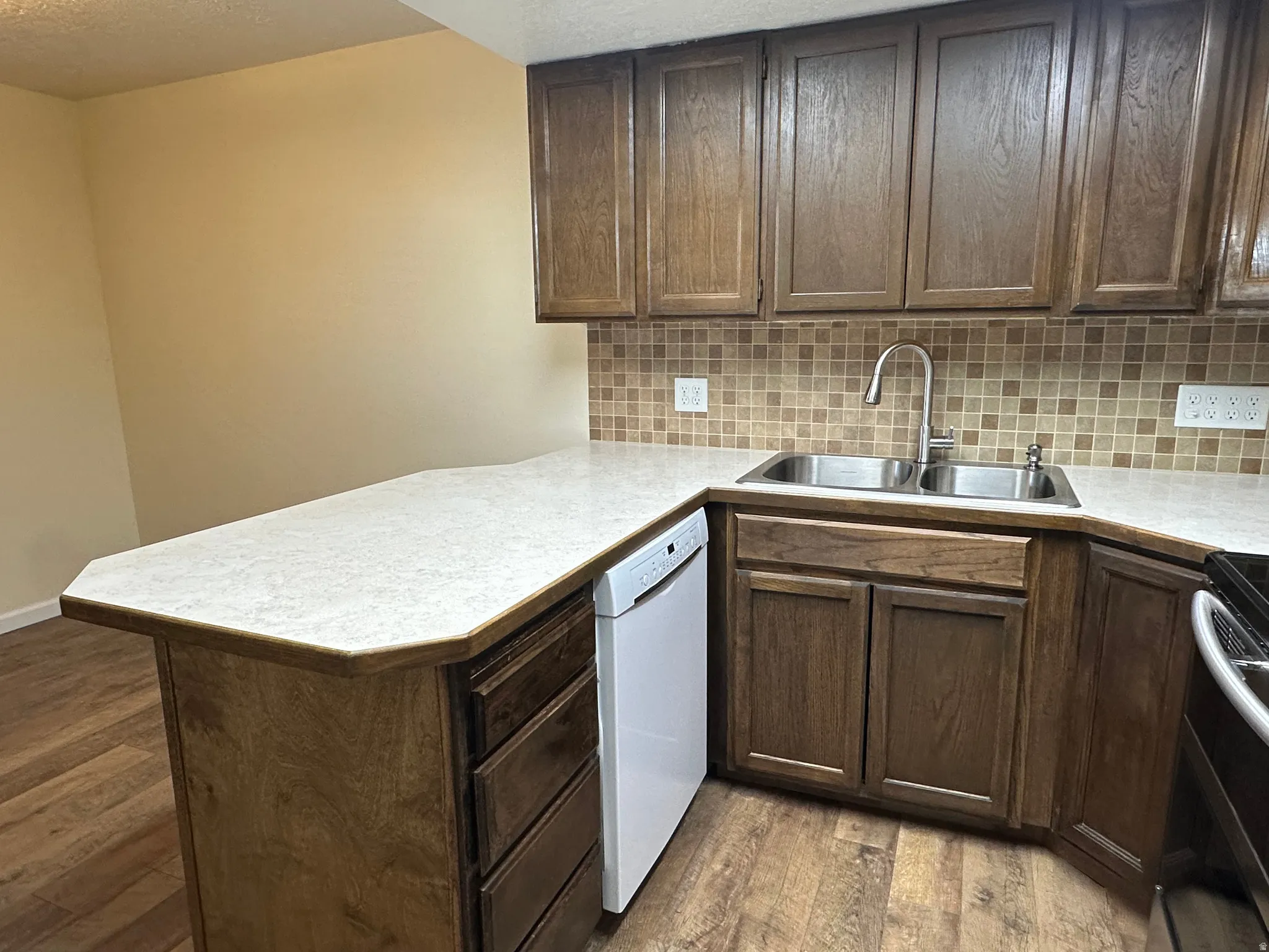 Kitchen featuring dark wood finished floors, electric range, light countertops, a peninsula, and dark wood finish cabinetry