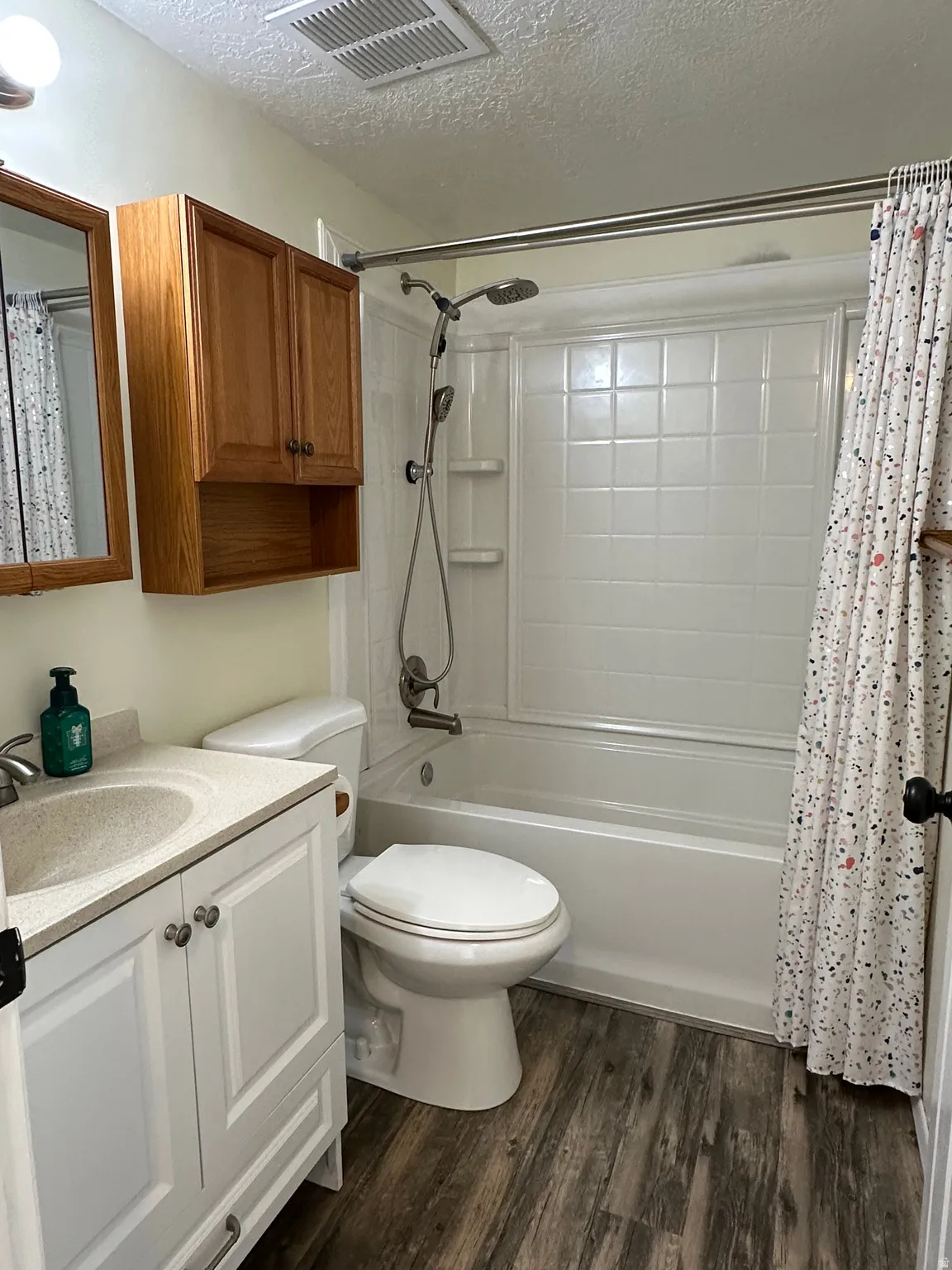 Bathroom featuring vanity, a textured ceiling, dark wood-type flooring, and shower / bath combo with shower curtain