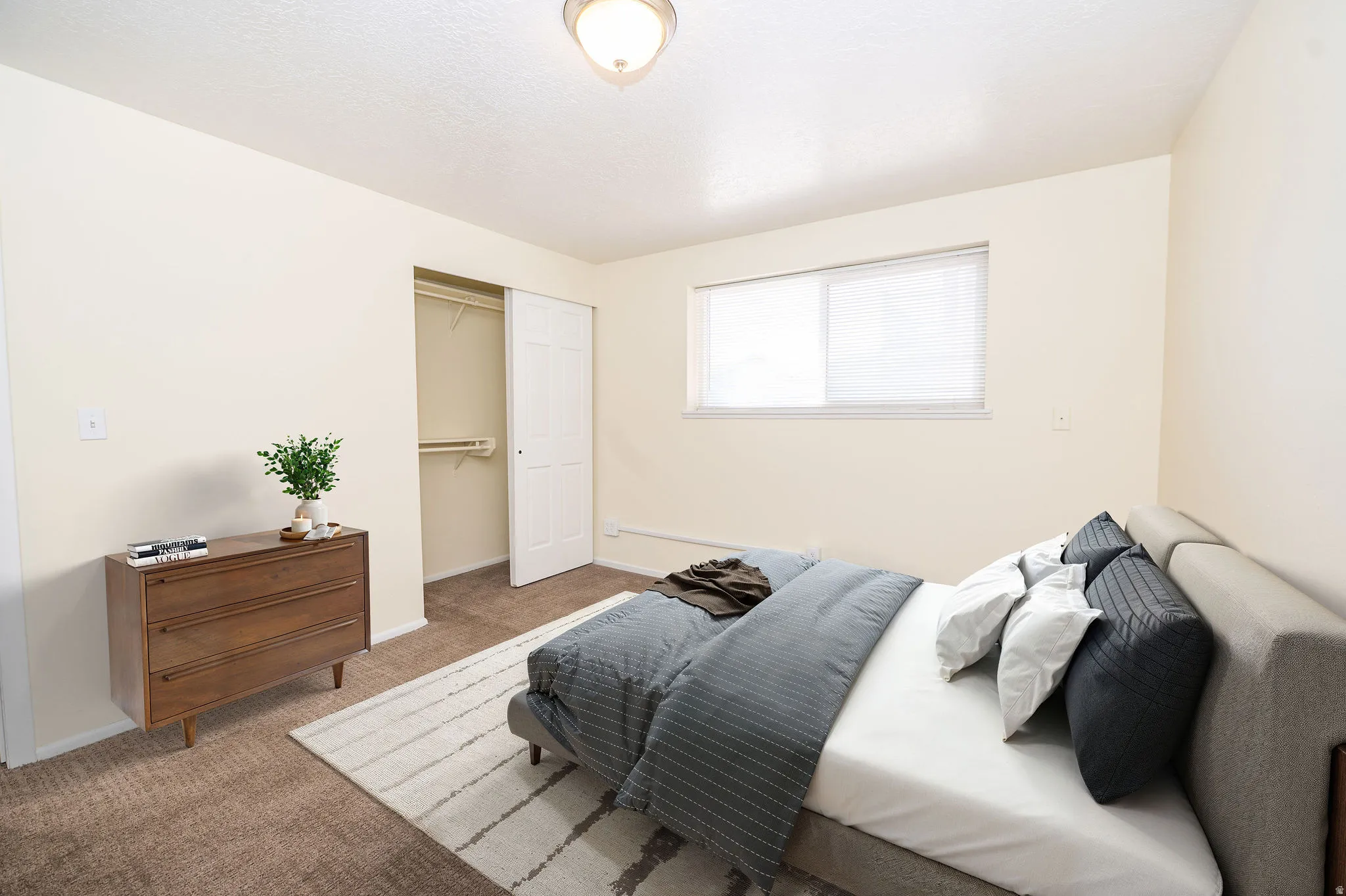 Bedroom featuring carpet flooring, a window with blinds, and a built-in closet with bi-fold doors