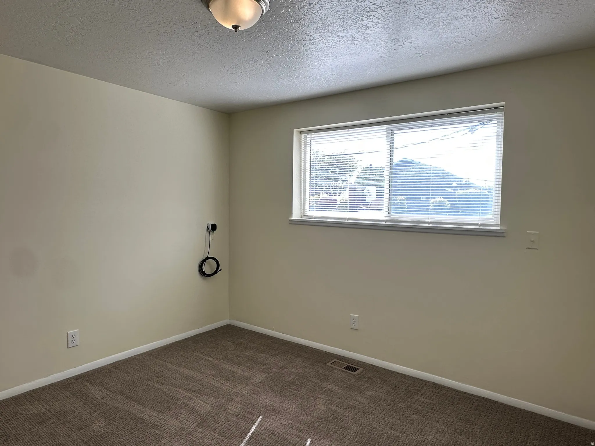 Spare room with a textured ceiling and dark colored carpet