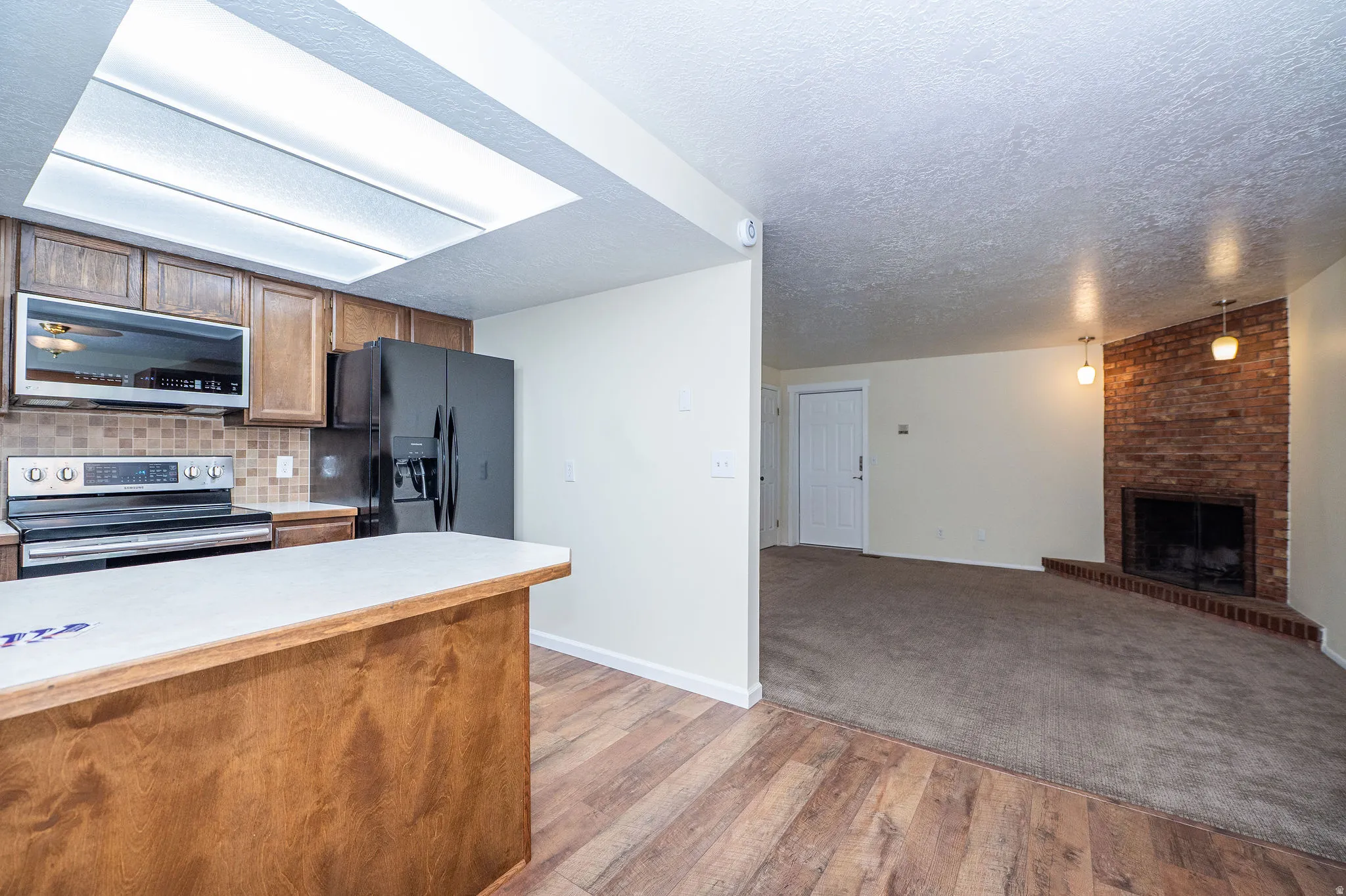 Open-concept living area featuring a kitchen with wood cabinetry, stainless steel range, and black refrigerator