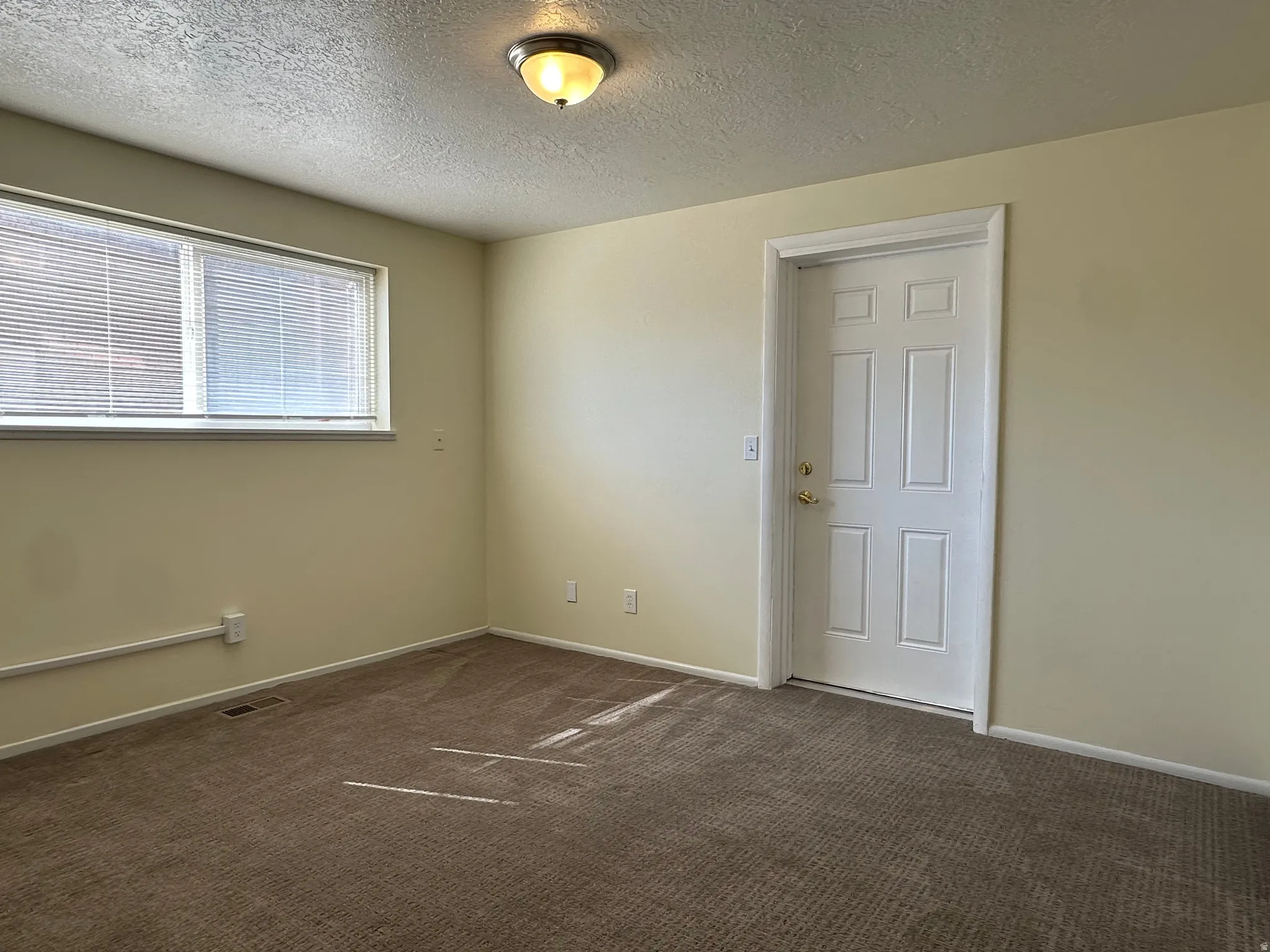 Spare room with a textured ceiling and dark colored carpet