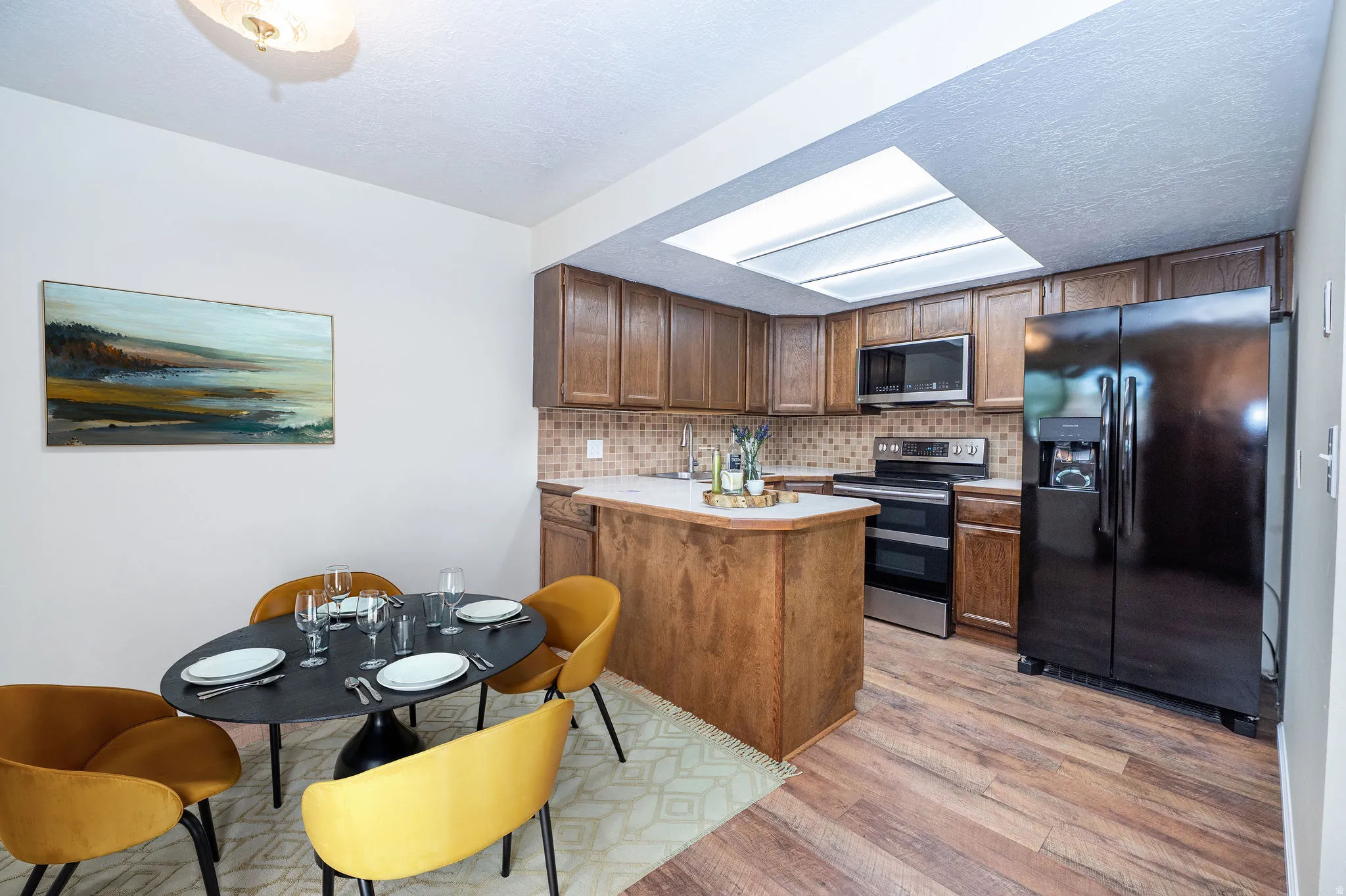 Kitchen featuring wood-finish flooring, wood cabinetry, a built-in microwave, and a black side-by-side refrigerator