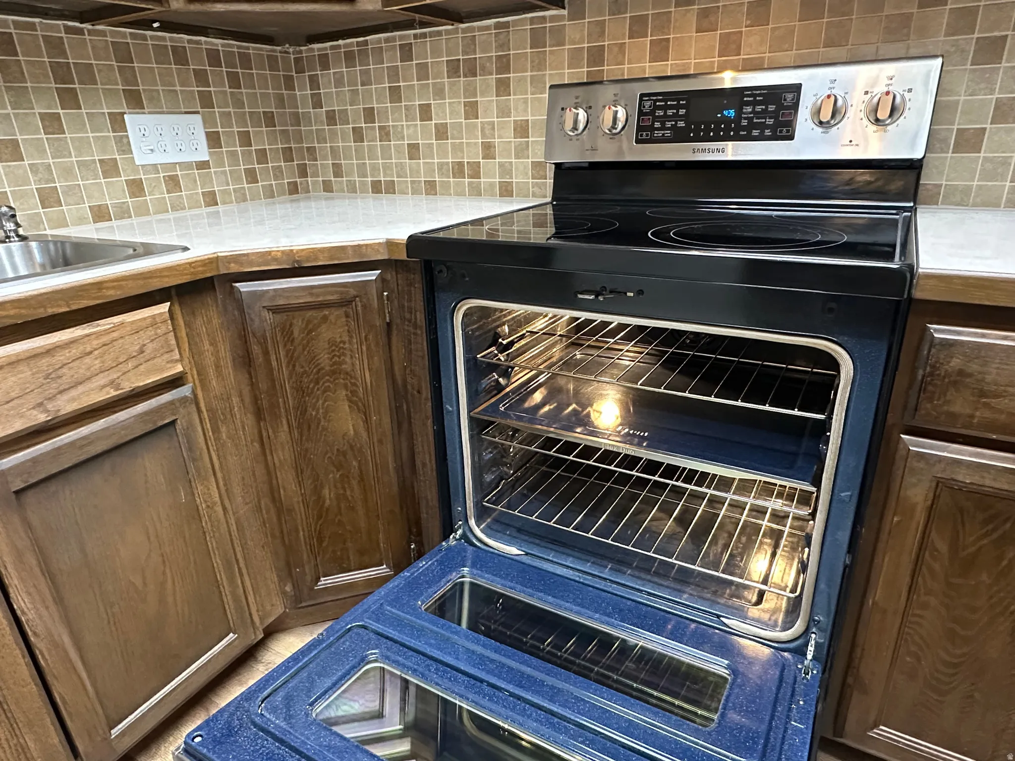 Kitchen featuring electric range, light countertops, tasteful backsplash, and dark wood finish cabinetry