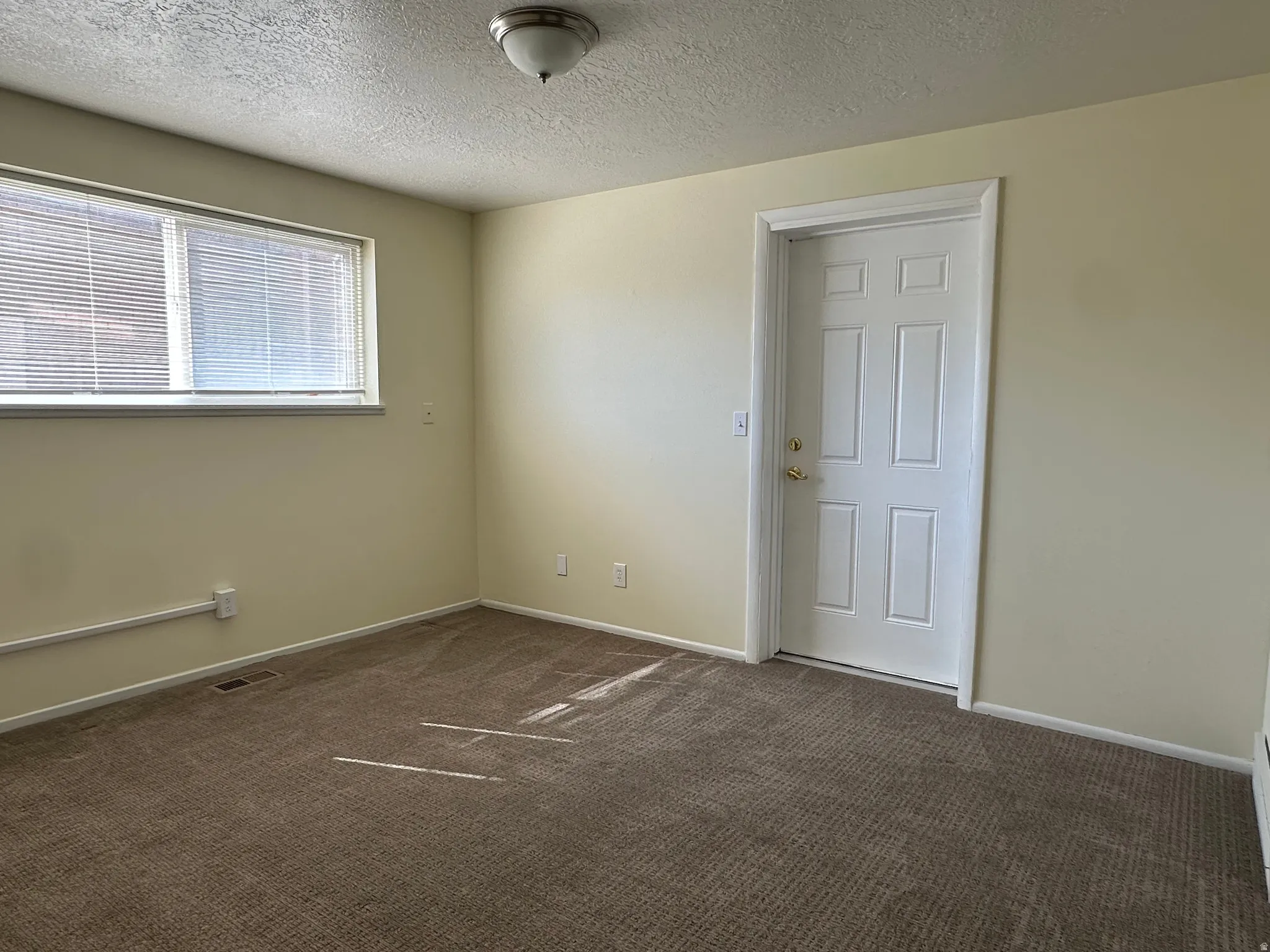 Spare room with dark carpet and a textured ceiling