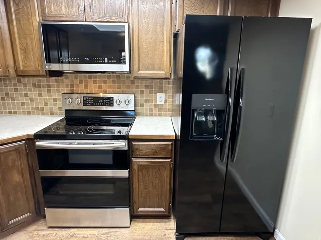 Kitchen featuring stainless steel appliances, light countertops, and backsplash
