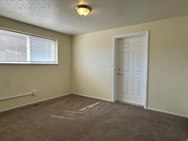 Spare room with a textured ceiling and dark colored carpet