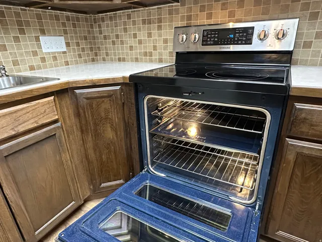 Kitchen featuring electric range, light countertops, tasteful backsplash, and dark wood finish cabinetry