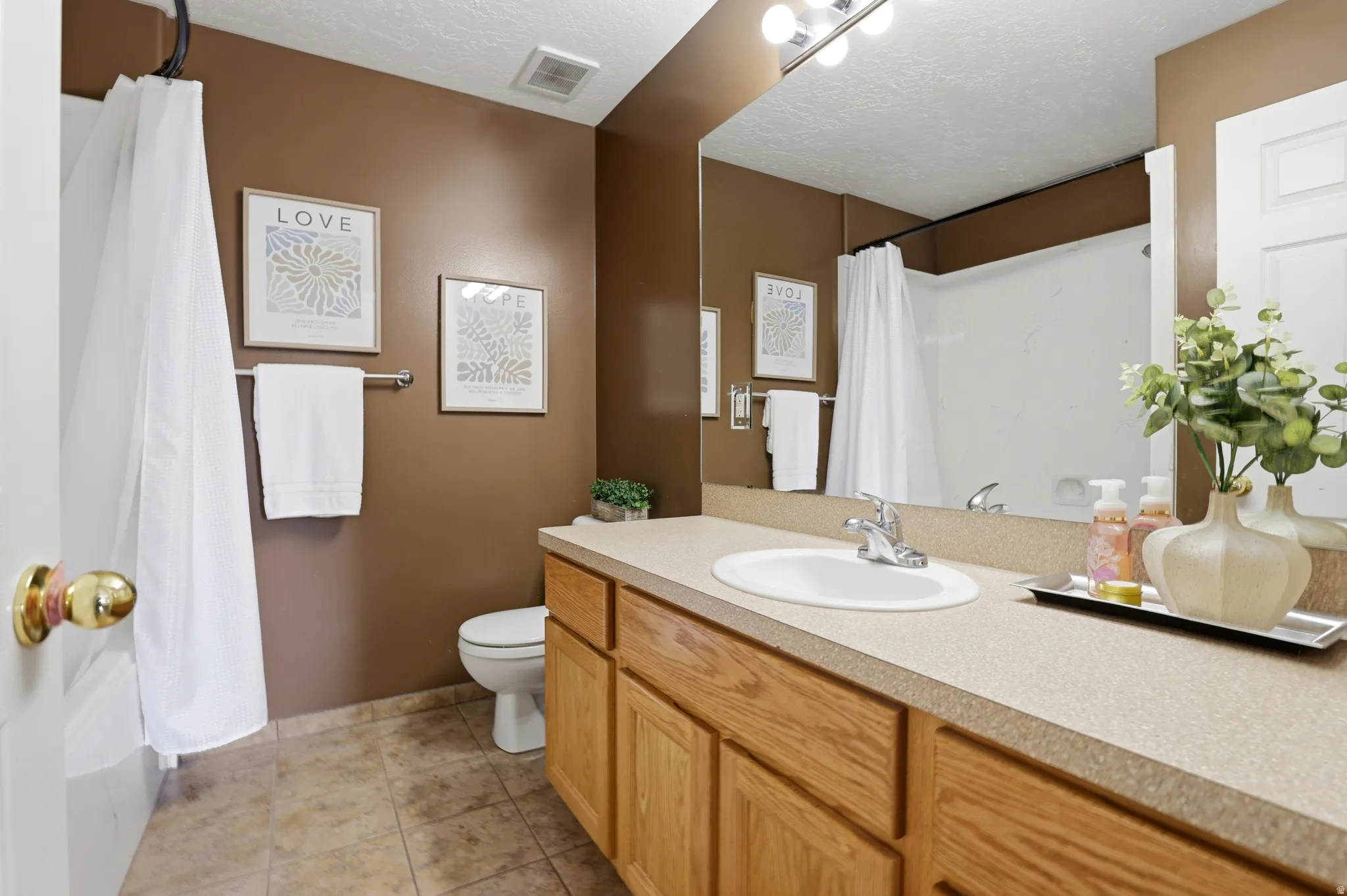 Full bathroom with vanity, a textured ceiling, and light tile patterned floors