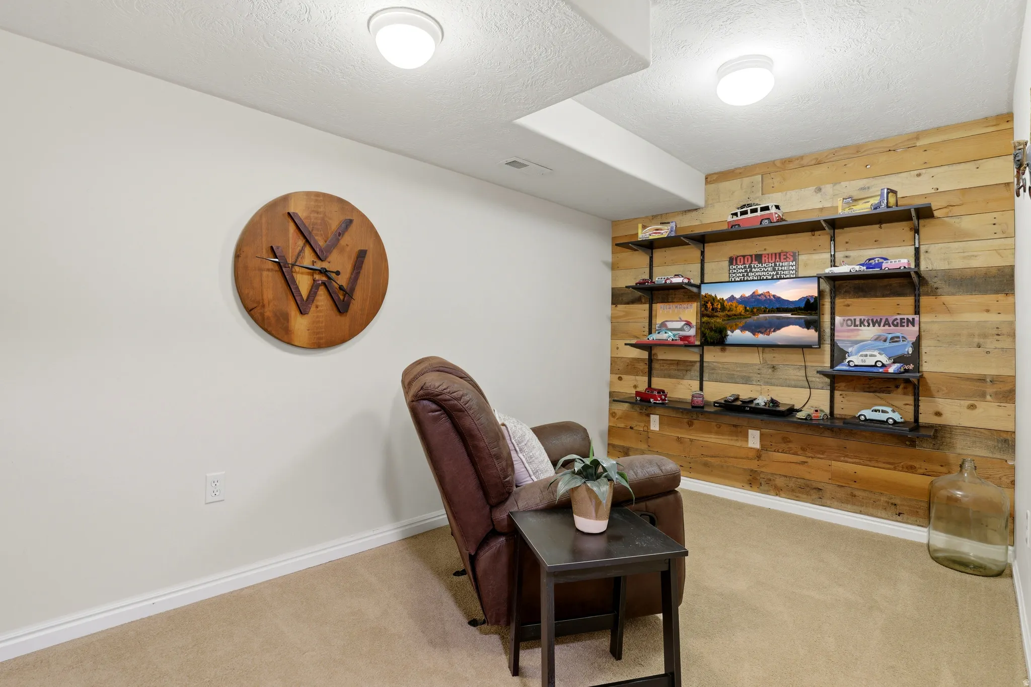 Sitting room featuring wooden walls, light colored carpet, and a textured ceiling