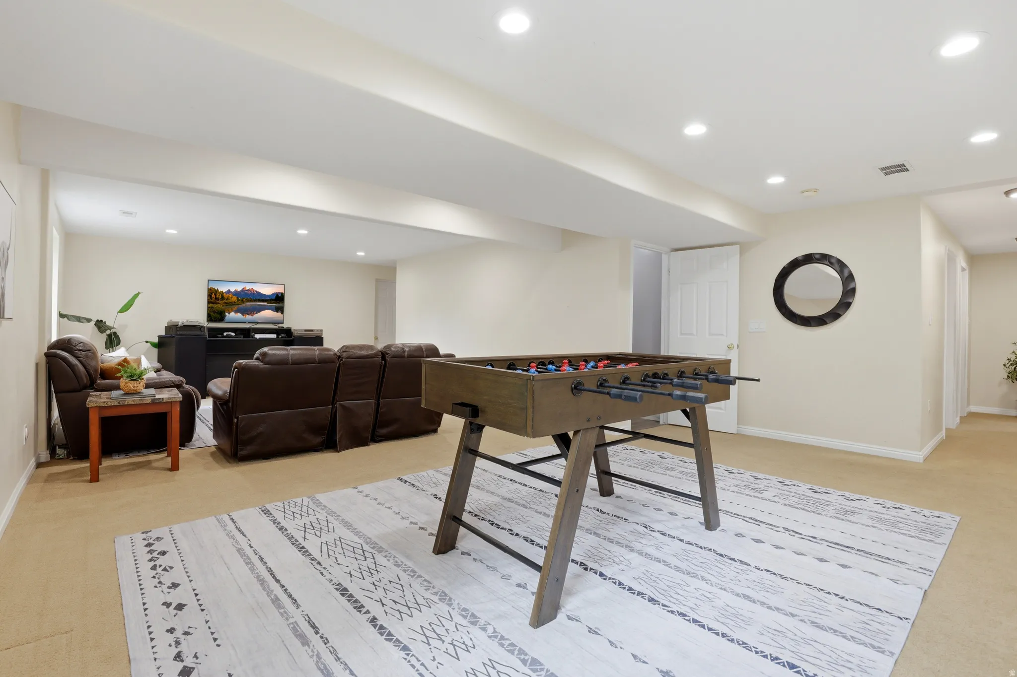 Recreation room with light carpet and recessed lighting