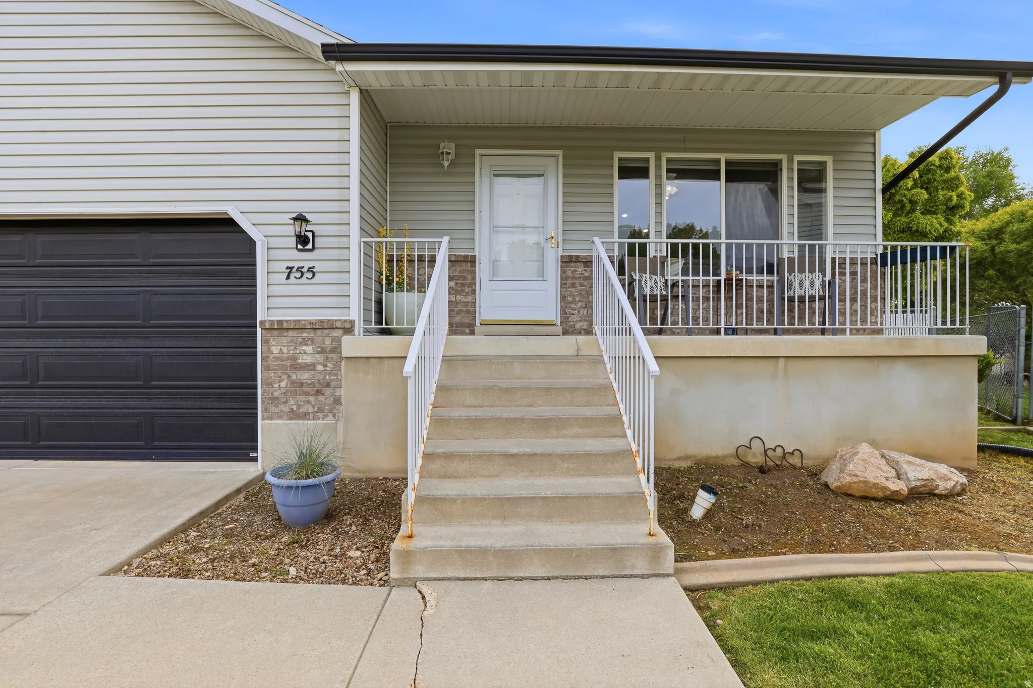 Doorway to property featuring covered porch, a garage, driveway, and brick siding