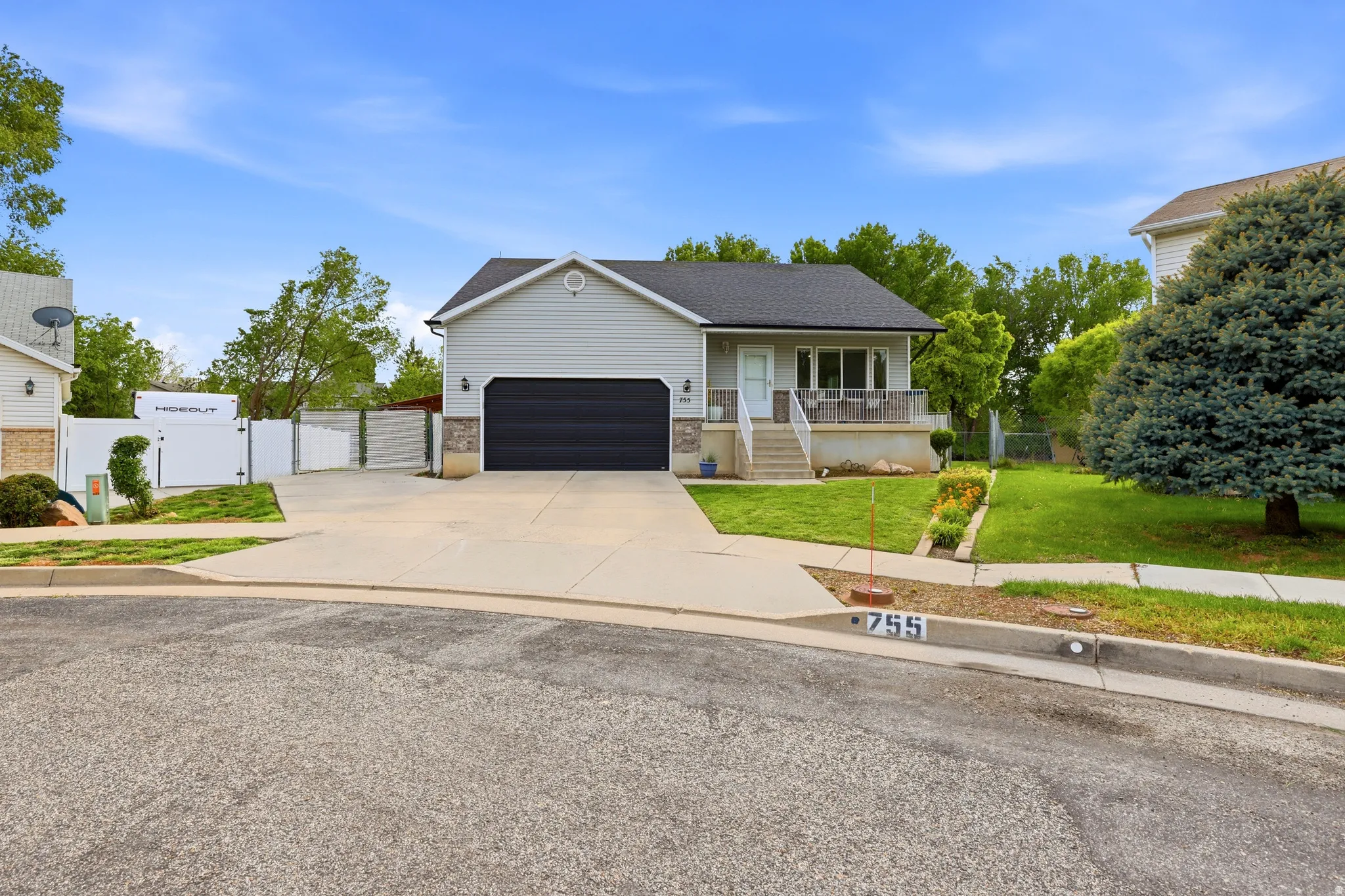 Ranch-style house with a gate, a porch, driveway, a garage, and brick siding