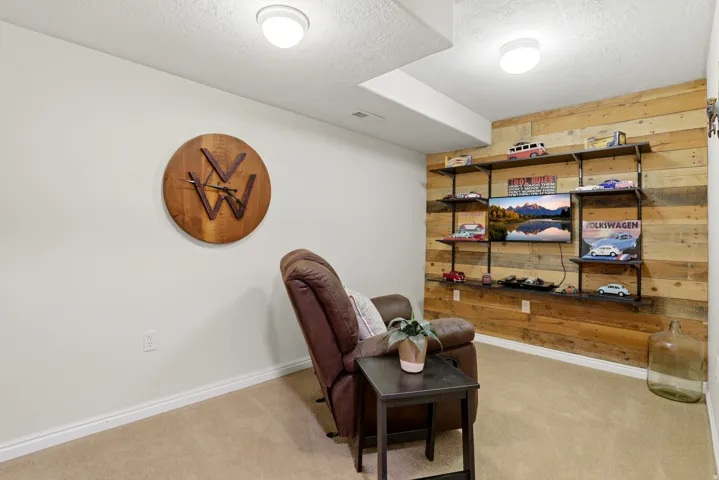 Sitting room featuring wooden walls, light colored carpet, and a textured ceiling