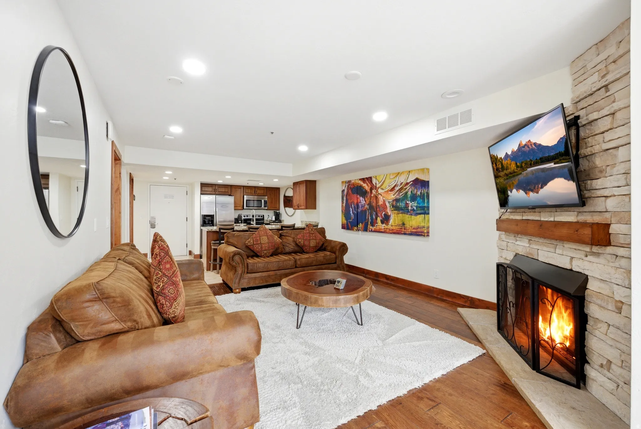 Living area featuring light wood-style floors, recessed lighting, and a stone fireplace