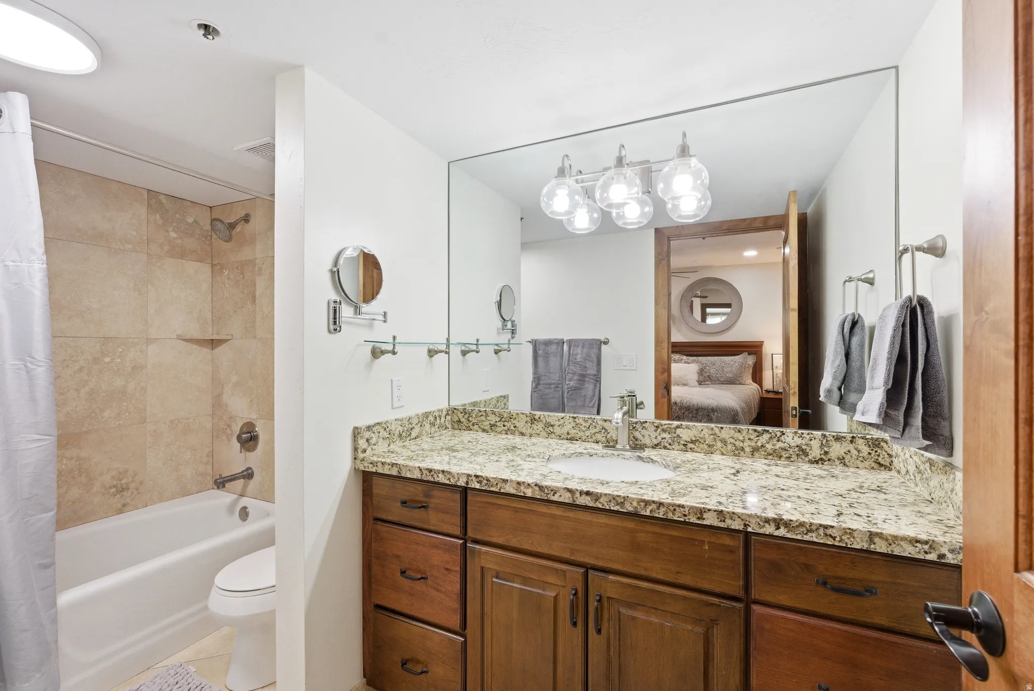 Bathroom featuring vanity, ensuite bathroom, shower / bathtub combination with curtain, and light tile patterned floors