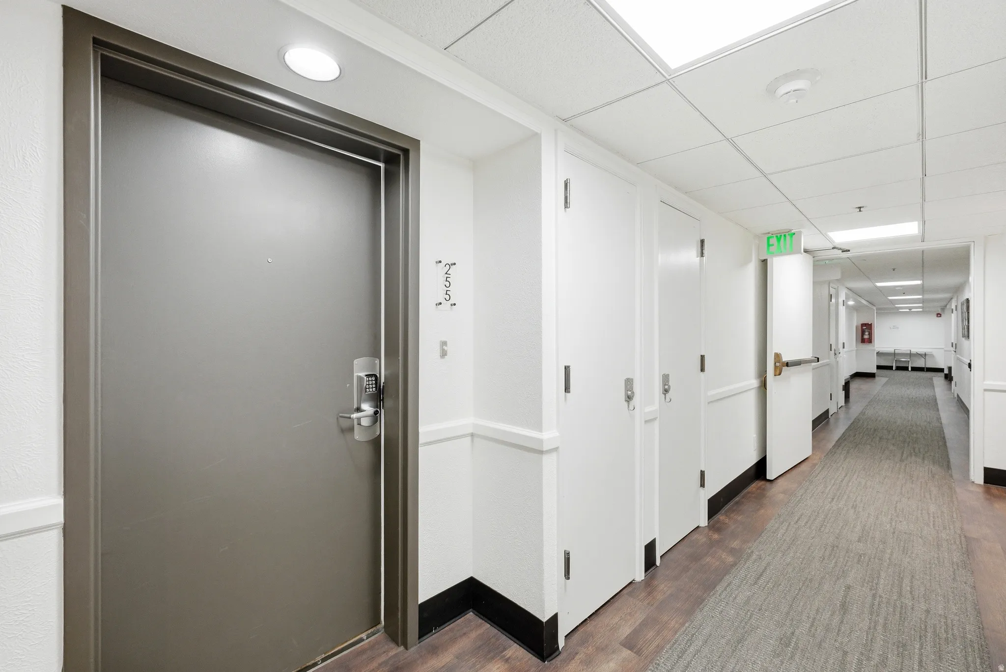 Corridor featuring a drop ceiling and dark wood-style flooring