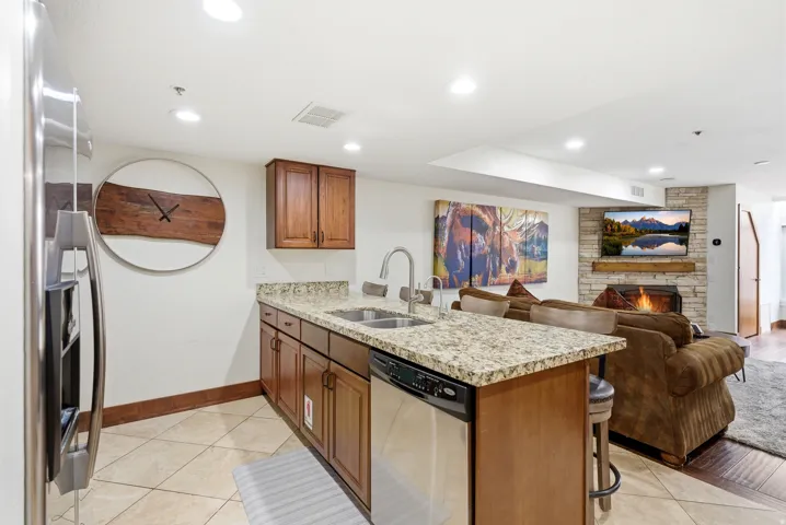 Kitchen with a peninsula, light stone counters, a fireplace, wood finish cabinets, and a kitchen breakfast bar