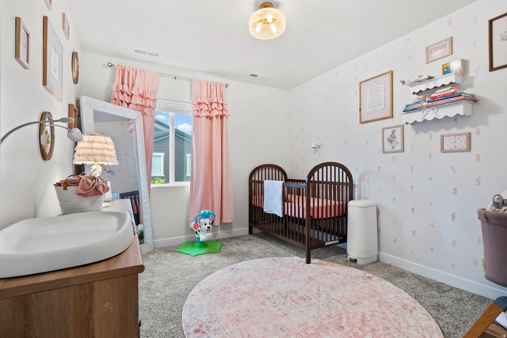 Bedroom featuring wallpapered walls, light colored carpet, and a nursery area