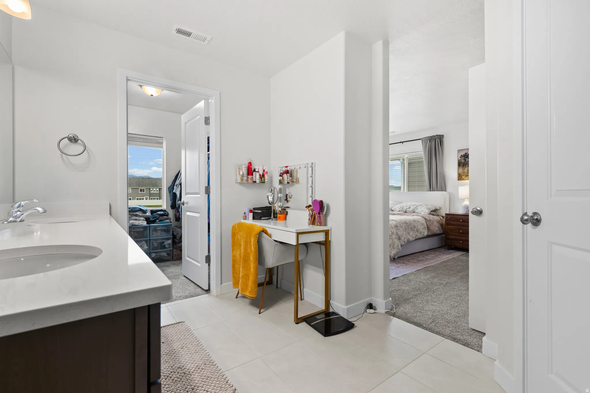 Ensuite bathroom featuring light carpet, double vanity, and healthy amount of natural light