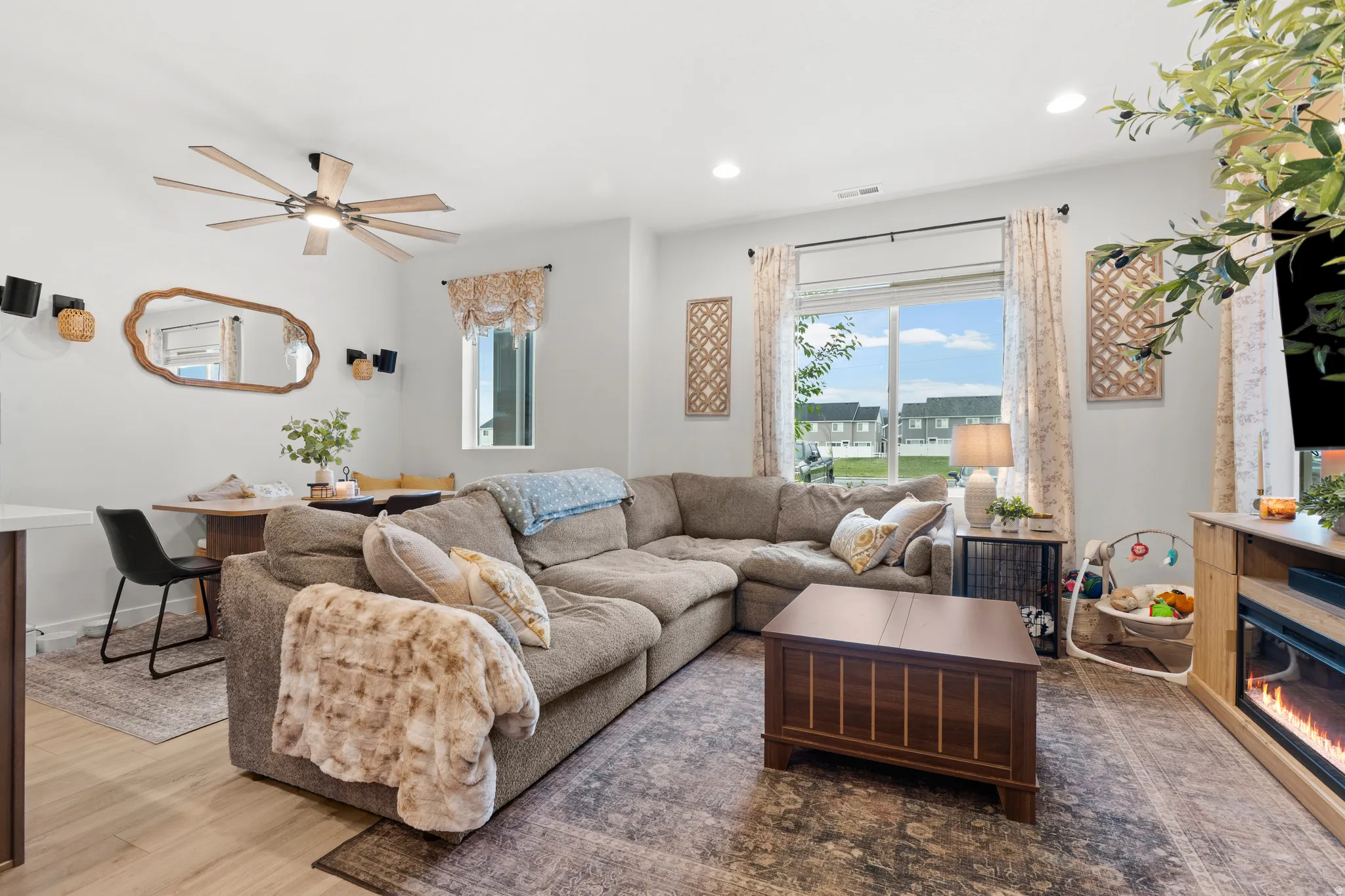 Living room with wood finished floors, a ceiling fan, recessed lighting, and a glass covered fireplace
