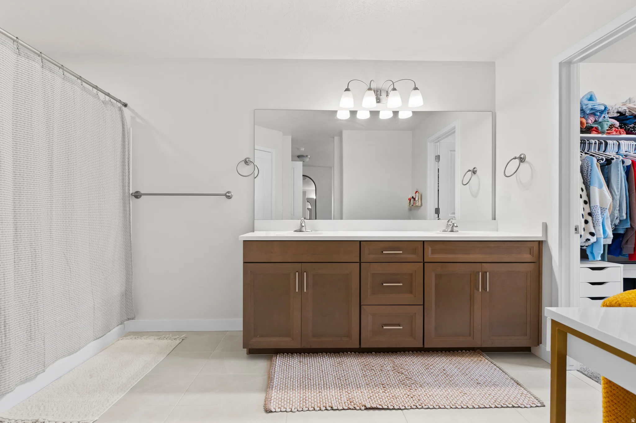 Bathroom with double vanity, curtained shower, a walk in closet, and light tile patterned flooring
