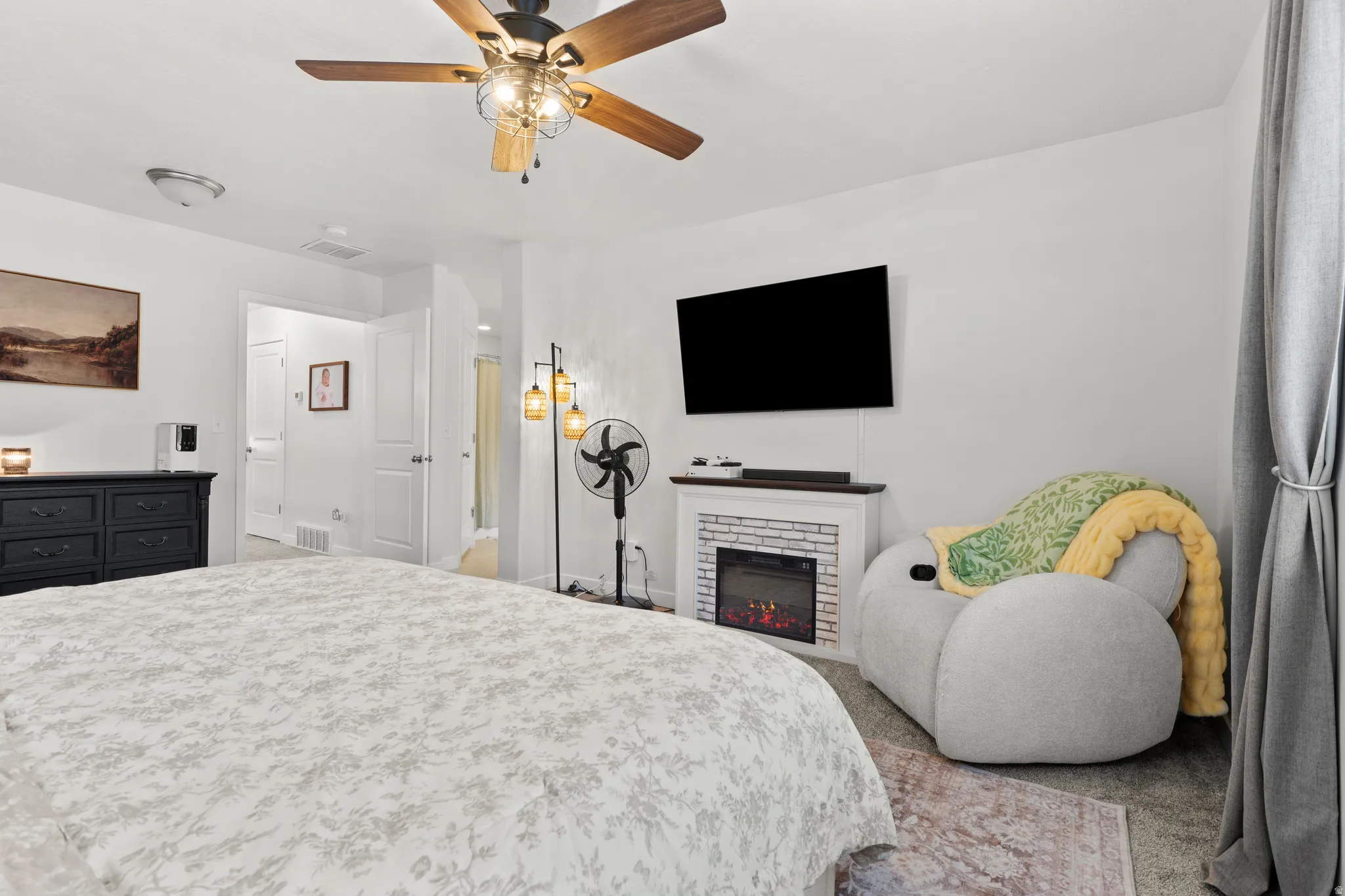 Carpeted bedroom featuring a brick fireplace and a ceiling fan