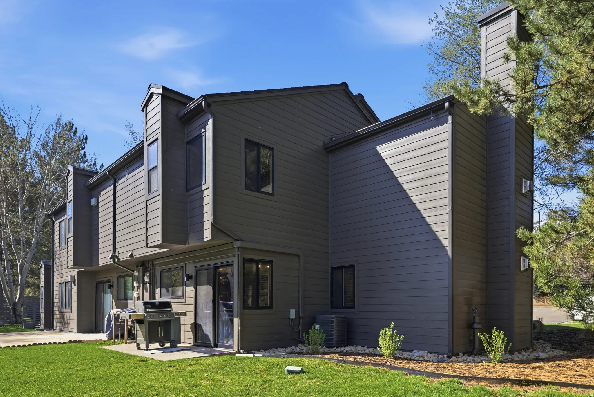 Back of house with a chimney, a lawn, and a patio area