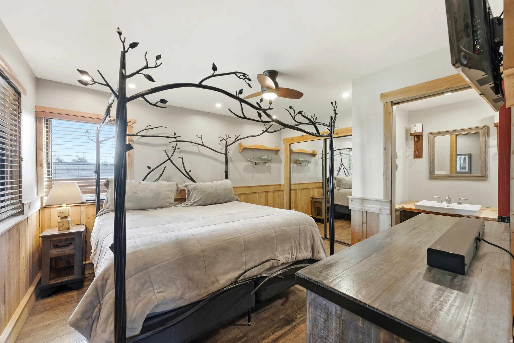 Bedroom with wooden walls, a wainscoted wall, and wood finished floors