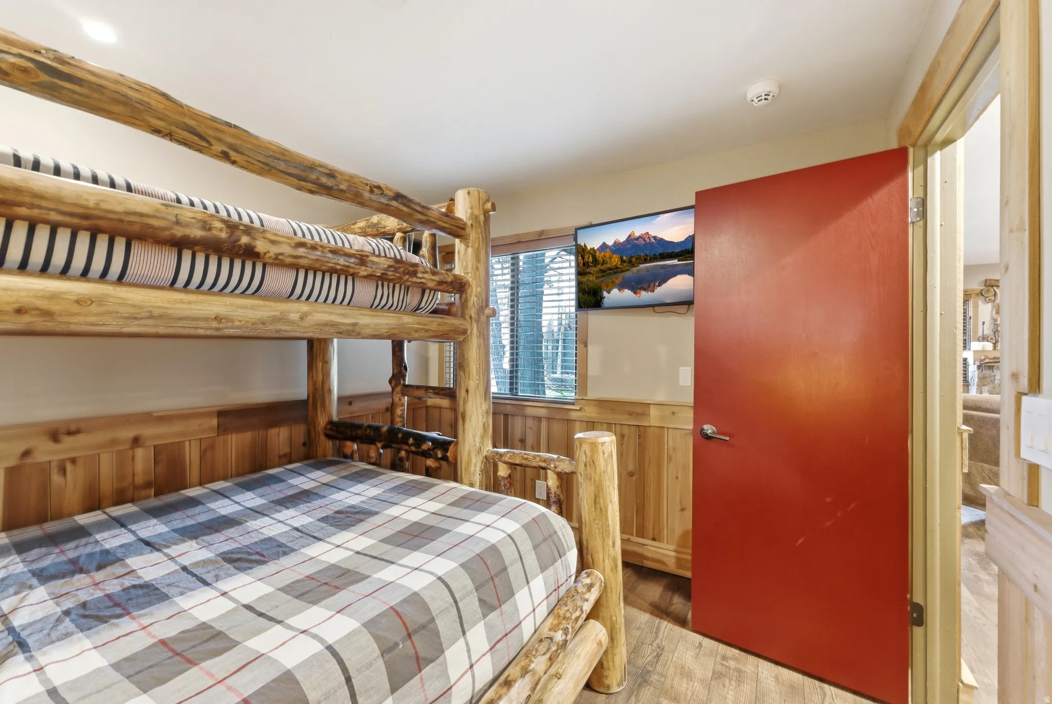 Bedroom featuring a wainscoted wall, wooden walls, and light wood-type flooring