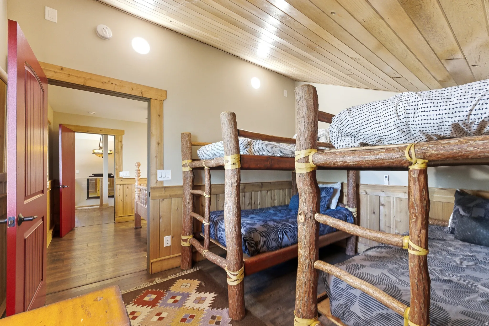 Bedroom featuring wainscoting, dark wood-style floors, wood ceiling, and wood walls